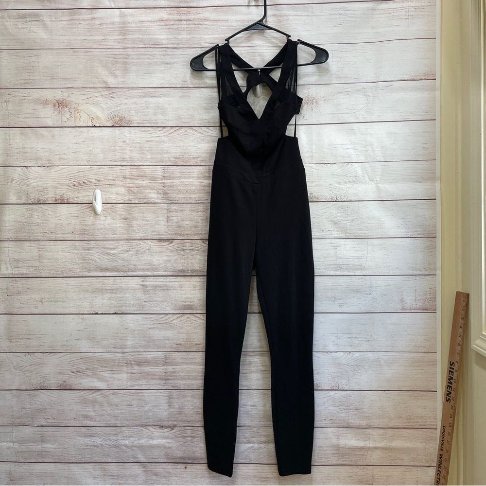 BEBE CROSSOVER BACK JUMPSUIT‎ WITH MESH ACCENTS IN BLACK